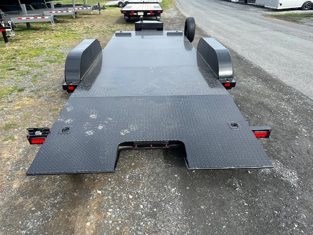 a black trailer is parked on the side of the road .