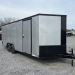 a gray and black trailer is parked in a gravel lot